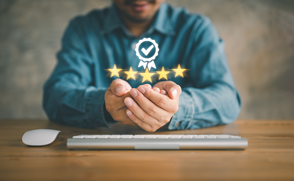 A person sitting at a desk with hands cupped under a glowing five-star rating and checkmark icon