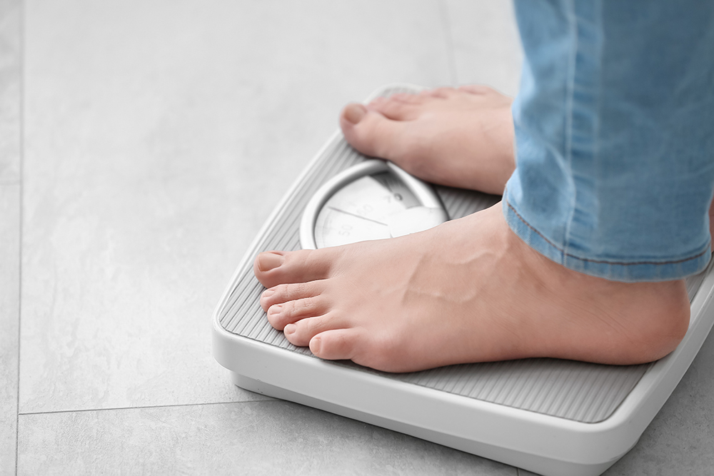 Bare feet standing on a weight scale with a tiled floor